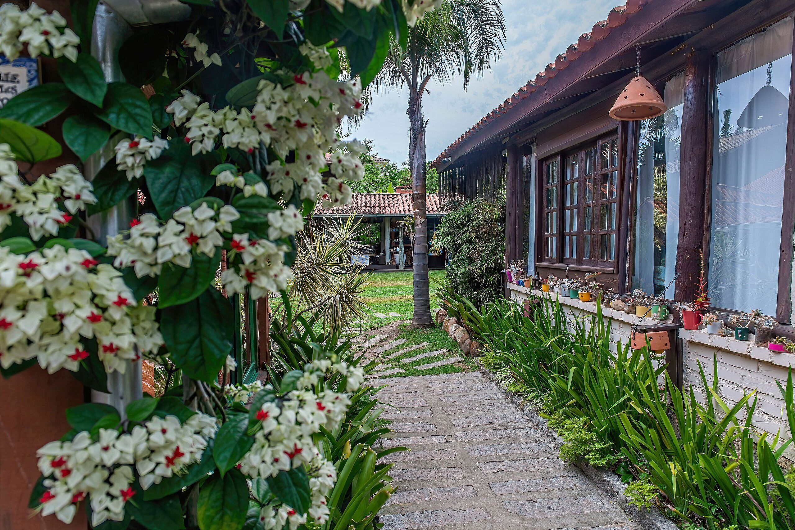 A pathway leading to a building with large windows and a tiled roof.
