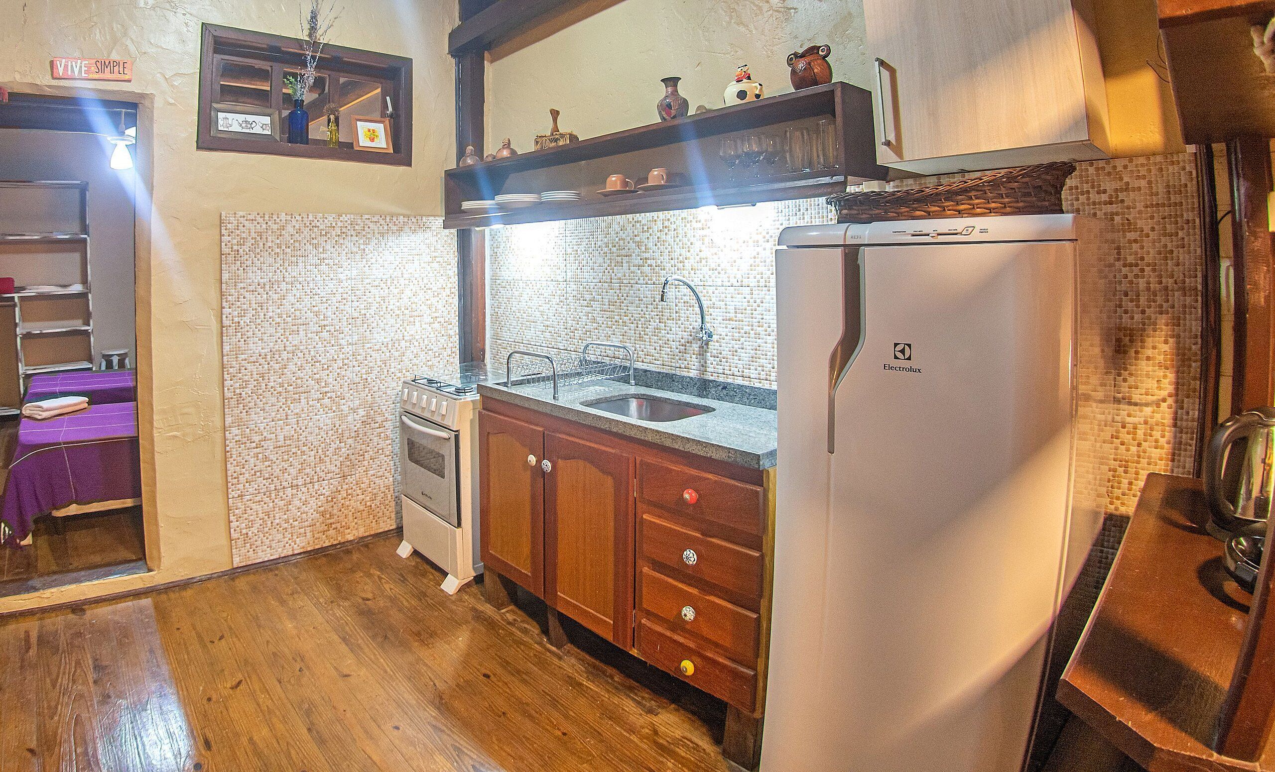 Una cocina compacta con armarios de madera, un refrigerador blanco, una estufa y un salpicadero de azulejos.