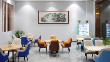 A conference room with tables and chairs, a framed artwork on the wall, and a vending machine.
