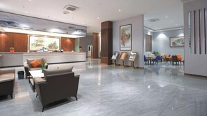 A modern lobby with a reception desk, seating area, and artwork.