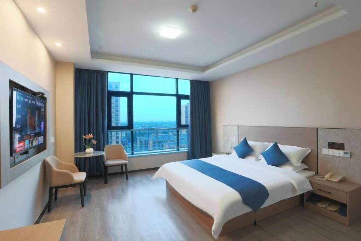 Une chambre d’hôtel avec un grand lit, un bureau, une chaise, une télévision et une vue sur la ville.