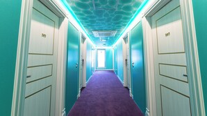 Un pasillo con paredes verde azulado, puertas blancas y una alfombra morada.