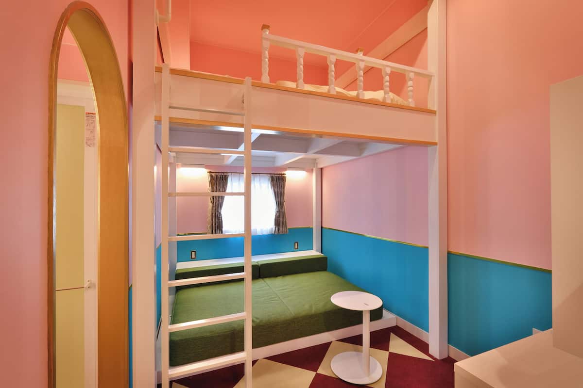 A bunk bed room with a small table and a window with curtains.