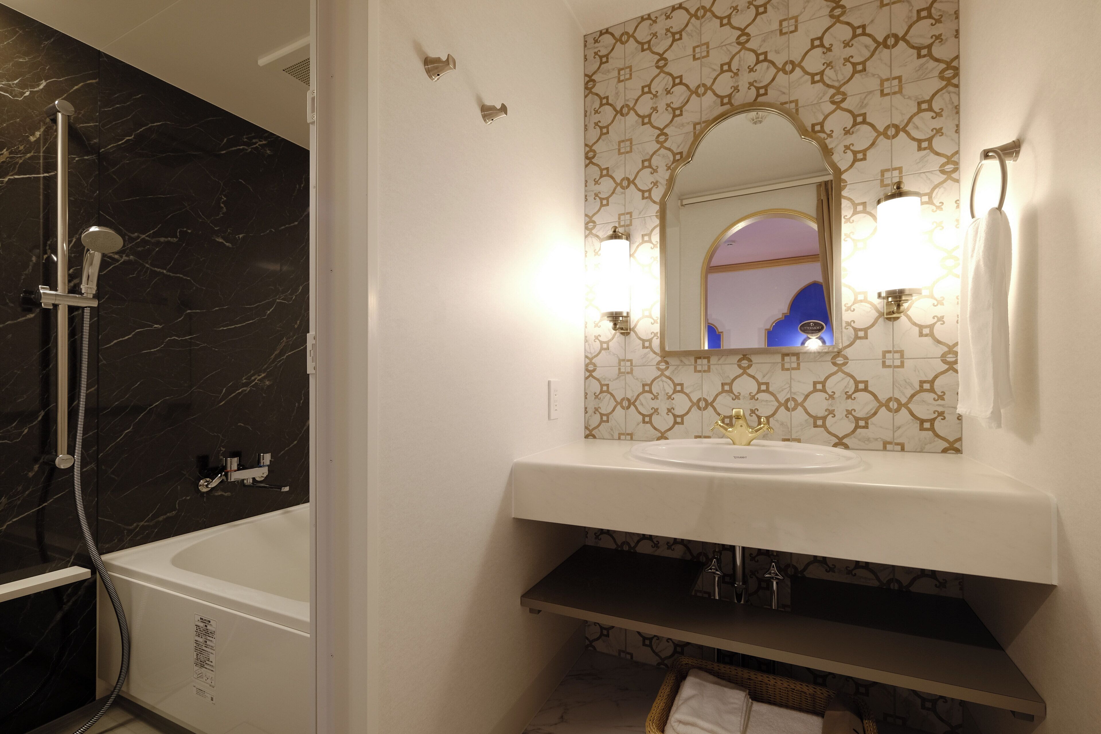 Un baño con bañera, lavamanos y espejo con apliques de pared.