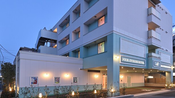 Un hotel de varios pisos con fachada plana, ventanas grandes y un cartel que dice "Four Stories Hotel".