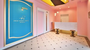 Un vestíbulo de hotel con pared azul, un mostrador de recepción y suelo de baldosas.