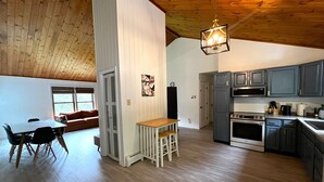 Eine geräumige Küche mit Holzböden, ein Essbereich mit Tisch und Stühlen und ein gemütliches Wohnzimmer mit einer Couch.