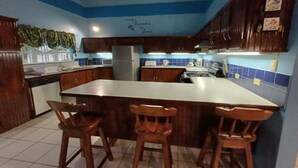 Een keuken met een centraal eiland, houten stoelen en blauwe betegelde muren.
