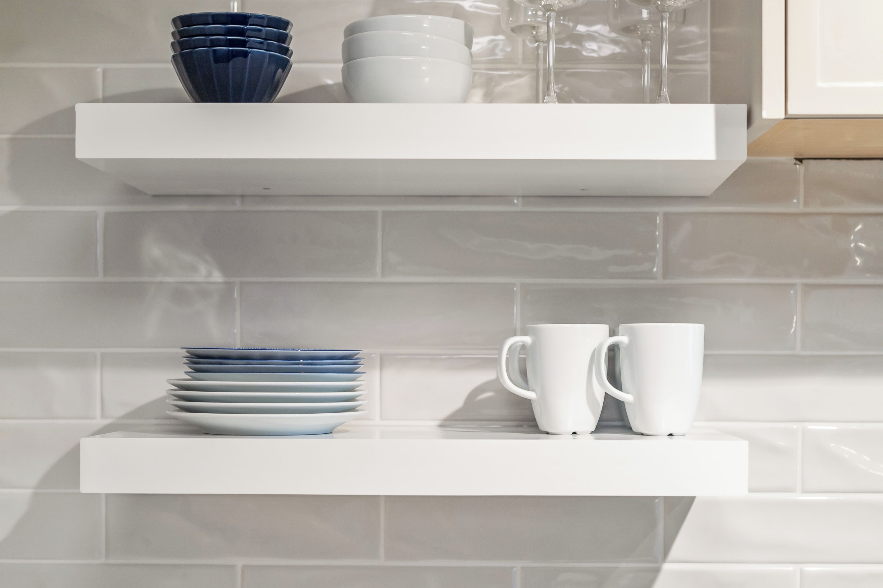 Une étagère blanche avec des assiettes et des tasses blanches empilées.
