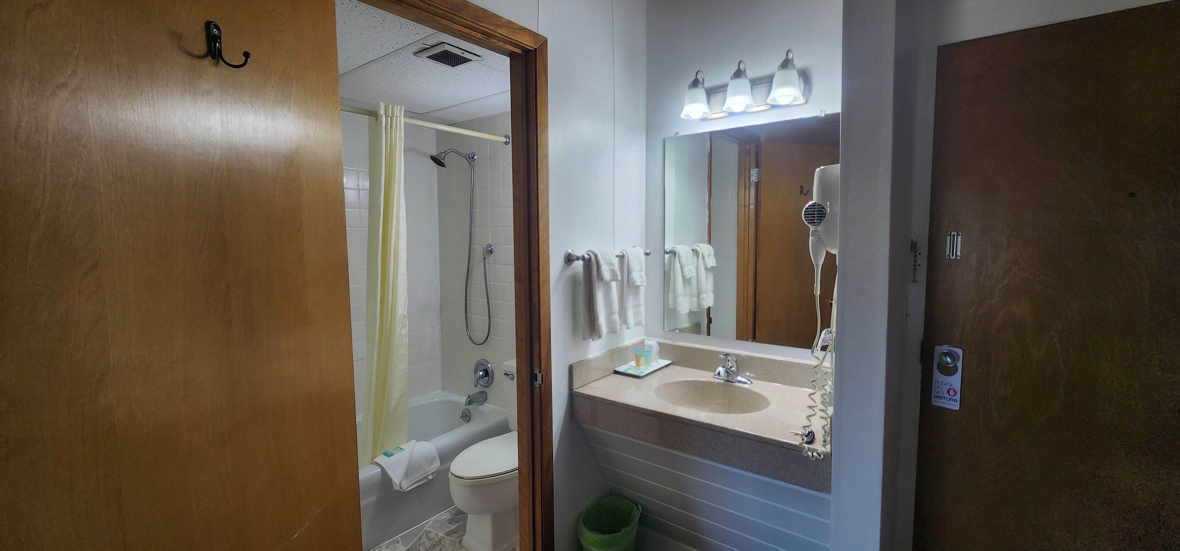 Une salle de bain équipée d’une douche, de toilettes, d’un lavabo et d’un miroir avec des lumières au-dessus.