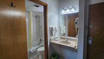 Une salle de bain équipée d’une douche, de toilettes, d’un lavabo et d’un miroir avec des lumières au-dessus.
