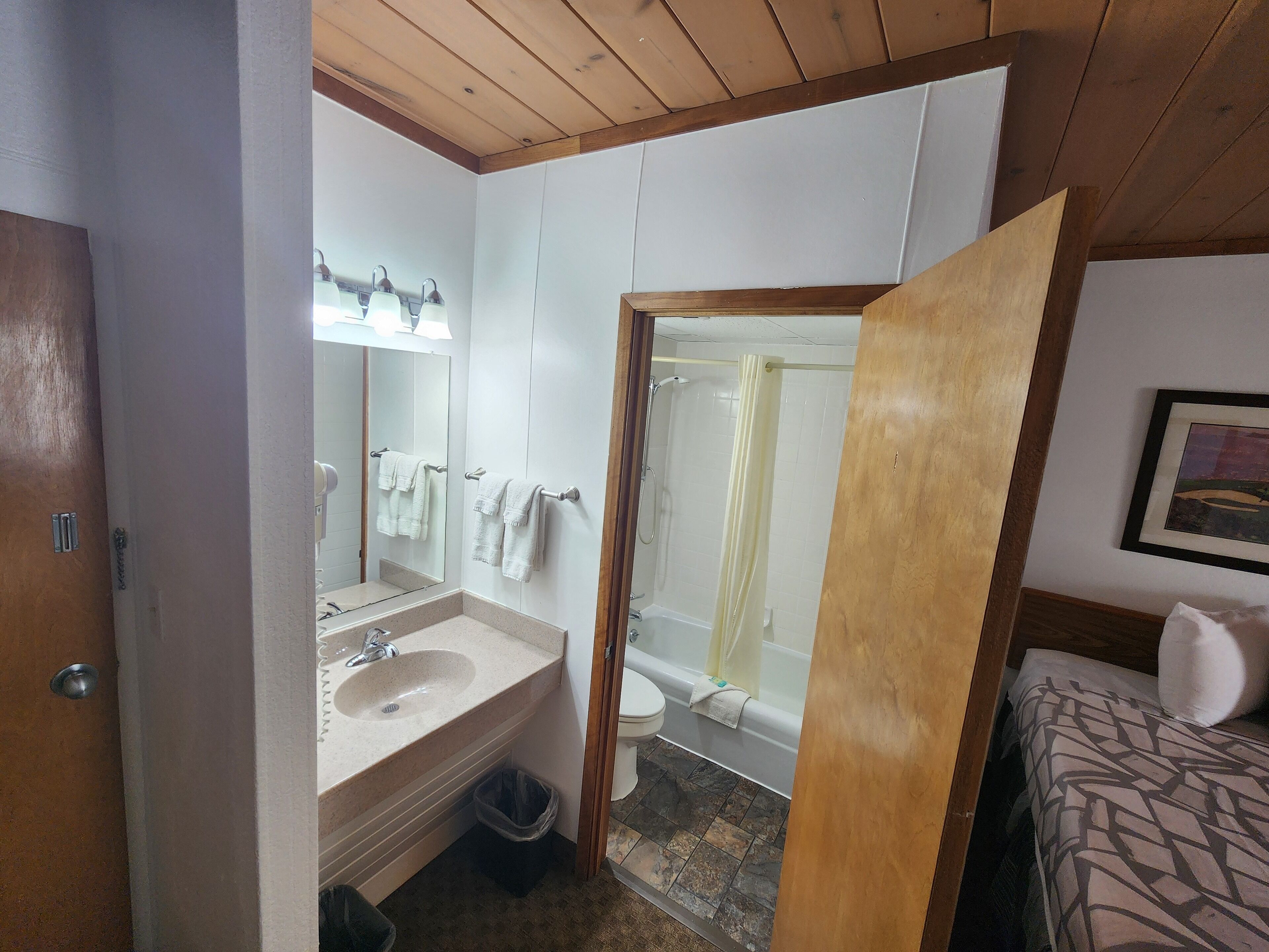 A bathroom with a sink, mirror, and shower.