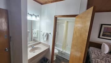 A bathroom with a sink, mirror, and shower.
