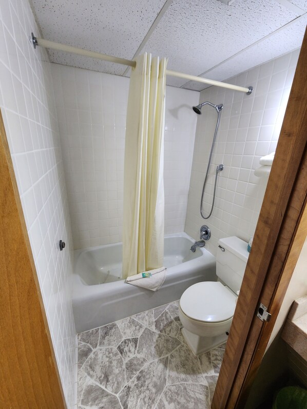 A bathroom with a bathtub, toilet, and shower. - Lantern Motel (Milbank)