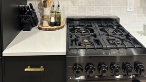 A kitchen with a gas stove, black cabinets, and white tiled backsplash. - Beautifully Remodeled Condo in Unbeatable Location! Walk to Gondola & Downtown (Ketchum)