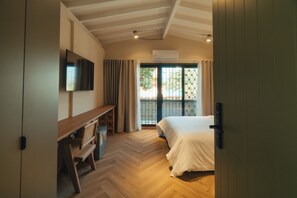 A bedroom with a bed, a TV mounted on the wall, a desk with a chair, and a window with curtains. - Hotel Botique Roomzz Laureles (Medellín)