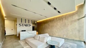 A modern living room with a white sofa, a round coffee table, and a reception desk with a 'START' sign. - Beautiful and Cozy Studio in San Jose (San José)