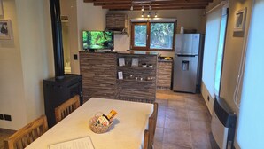 Una cucina con televisore, frigorifero e soffitto in legno.
