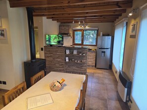 A kitchen with a TV, a refrigerator, and a wooden ceiling.