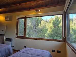 A room with two beds, a large window with a view of trees, and a ceiling fan. - Nature, Mountains & Relax - Casa Ciprés Bariloche (San Carlos de Bariloche)