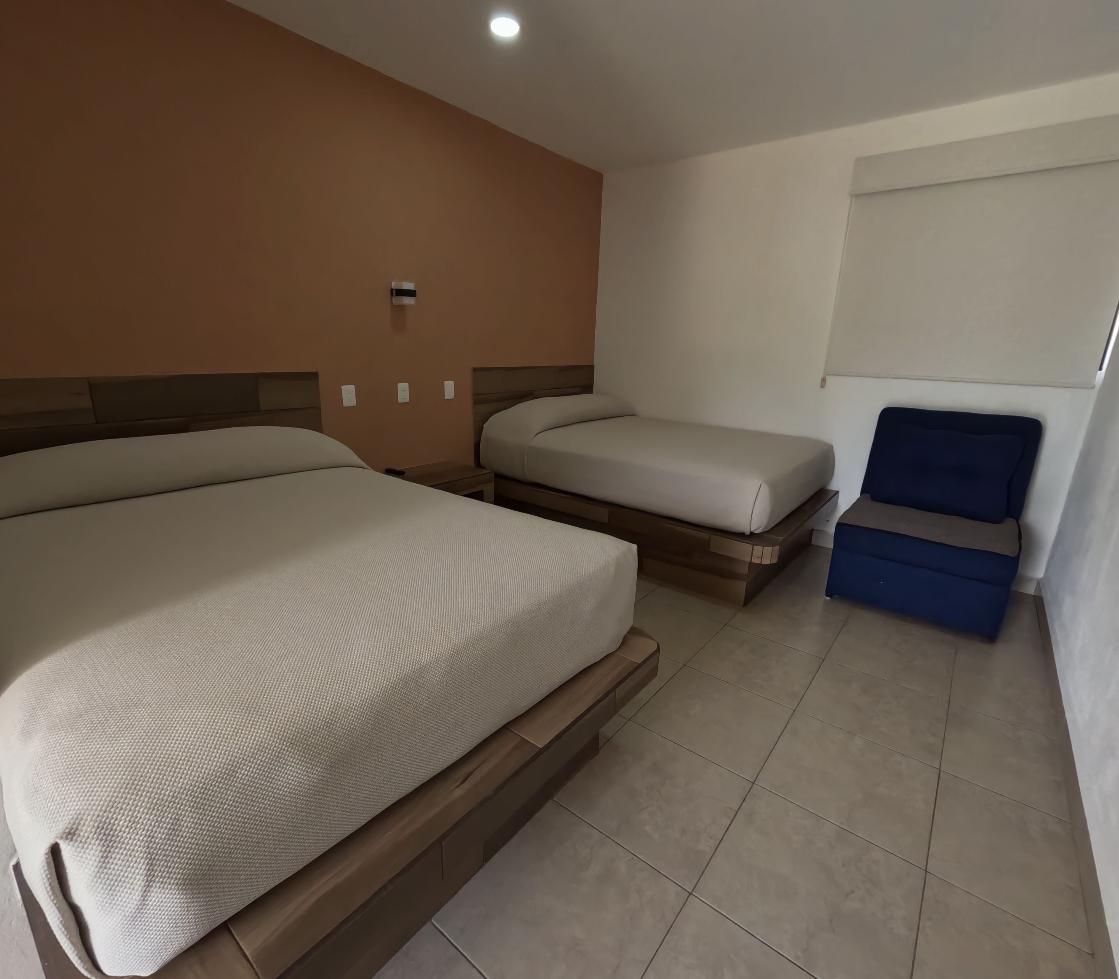 Una habitación de hotel con dos camas, una mesita y una silla.