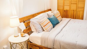 A neatly made bed with striped pillows, a bedside table with a lamp, and a wooden headboard. - Charming Casita - 3 BDRM Downtown (Bozeman)