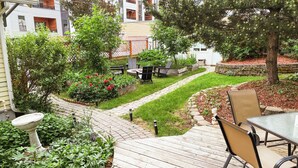 A wooden deck with outdoor furniture, a garden with various plants, and a stone pathway. - Charming Casita - 3 BDRM Downtown (Bozeman)