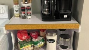 A kitchen counter with a coffee maker, spices, and a sugar container. - Cozy city cottage, one floor, covered porches, quiet neighborhood  (Newark)