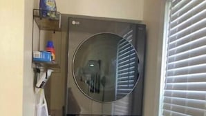 A compact, two-door washer and dryer unit in a small laundry room with a window and blinds. - Cozy city cottage, one floor, covered porches, quiet neighborhood  (Newark)