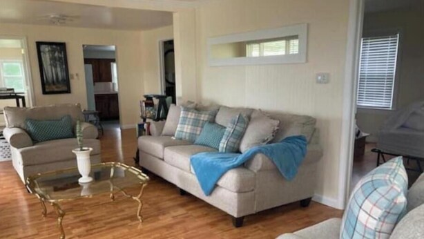 A living room with a beige sofa, a glass coffee table, and a wooden floor. - Cozy city cottage, one floor, covered porches, quiet neighborhood  (Newark)