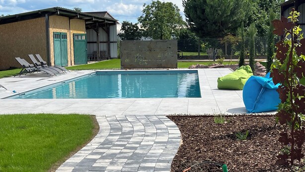 A swimming pool with a tiled deck, lounge chairs, and a covered seating area. - Gite 4 , 8 Pers, Proche Europapark, Piscine, Wellness, (Schœnau)