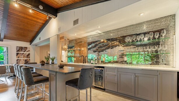 Une cuisine moderne dotée d’un bar, de tabourets de bar et d’un grand îlot central.