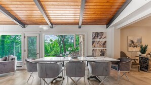 Un espace de restauration moderne avec un plafond en bois, de grandes fenêtres et une vue sur la verdure.