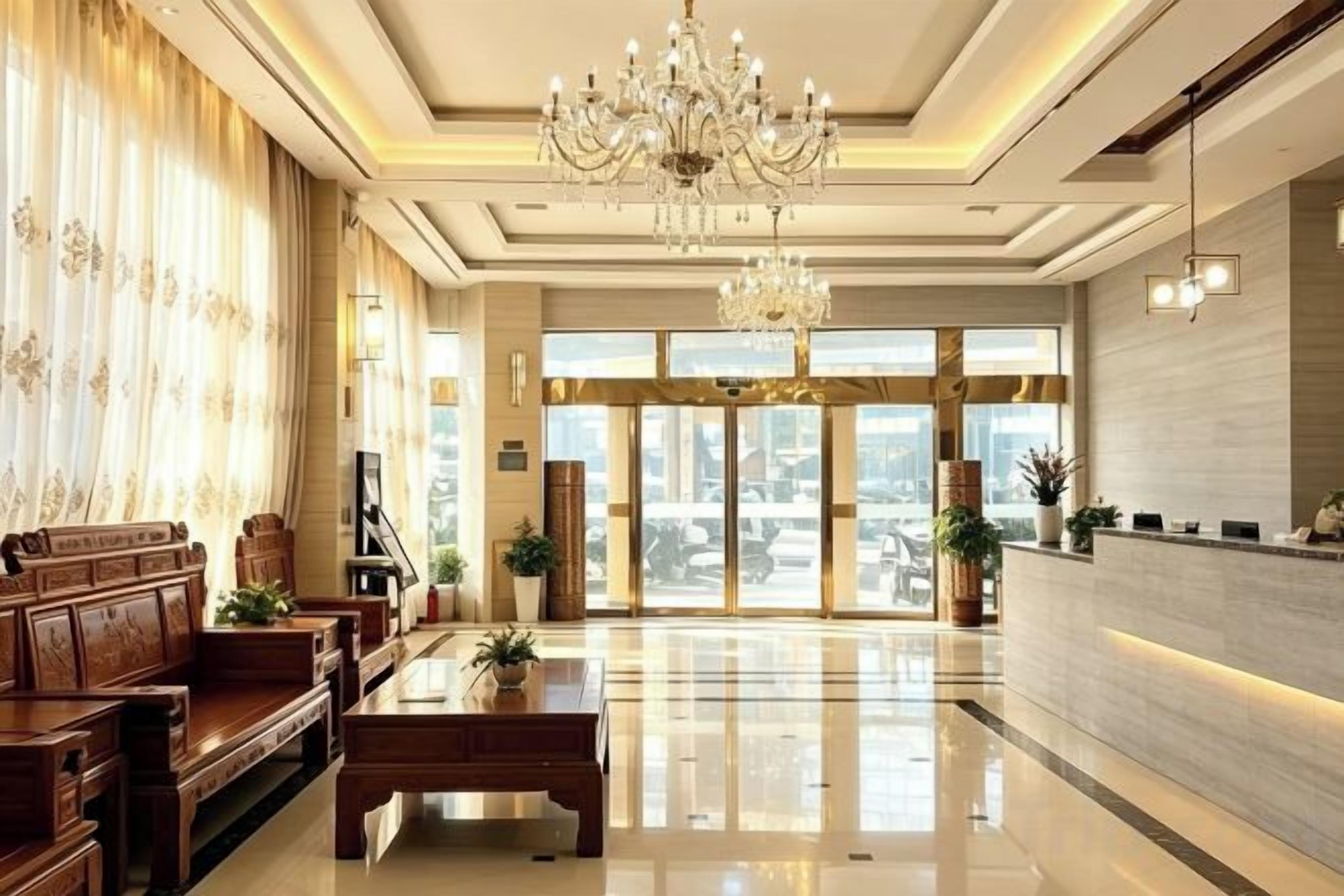 A hotel lobby with a reception desk, seating area, chandelier, and large windows.