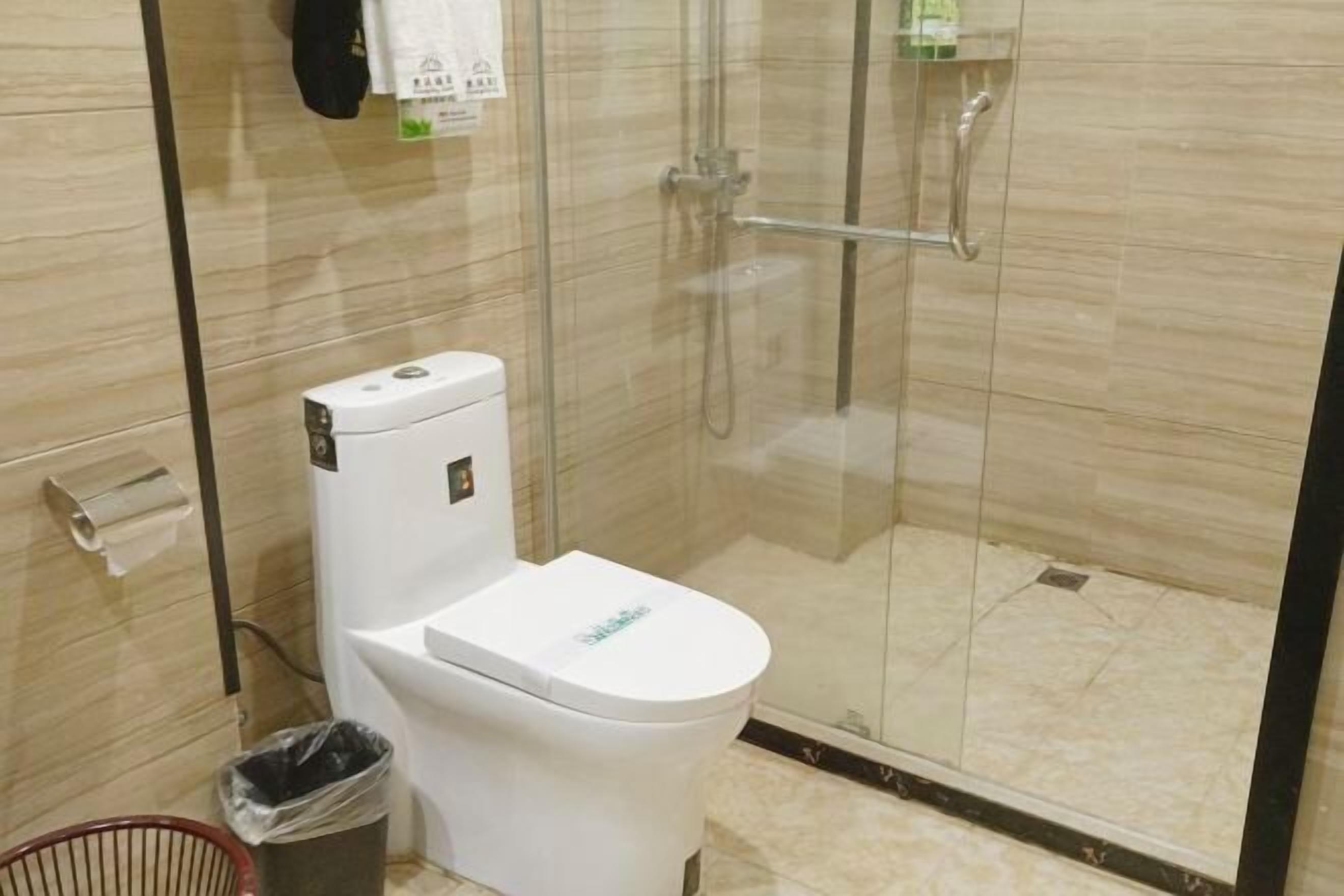 Une salle de bain moderne équipée de toilettes, d’une douche à parois de verre et d’une poubelle.