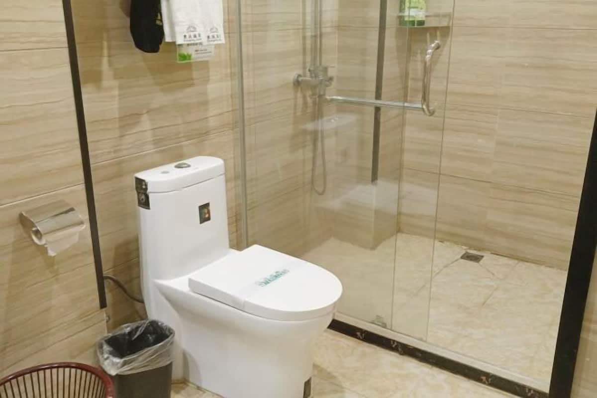 Une salle de bain moderne équipée de toilettes, d’une douche à parois de verre et d’une poubelle.