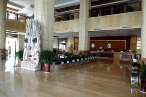 Un hall d’entrée spacieux agrémenté d’une grande sculpture abstraite, d’un comptoir de réception et de plusieurs niveaux de balcons.