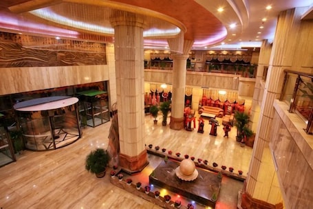 A hotel lobby with marble flooring, large columns, a central fountain, and a seating area with red decor.. Taoyuan International Hotel