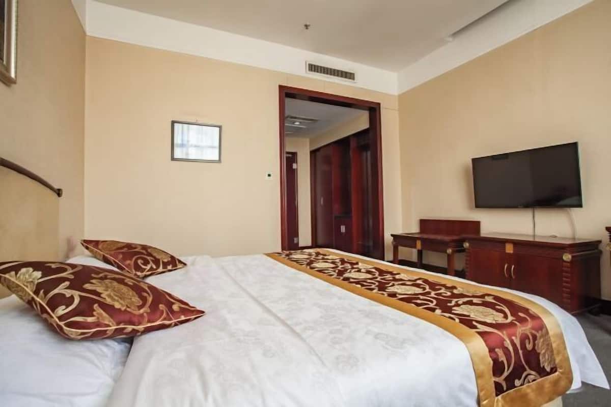 Une chambre d’hôtel équipée d’un lit, d’une télévision, d’un bureau et d’une armoire.