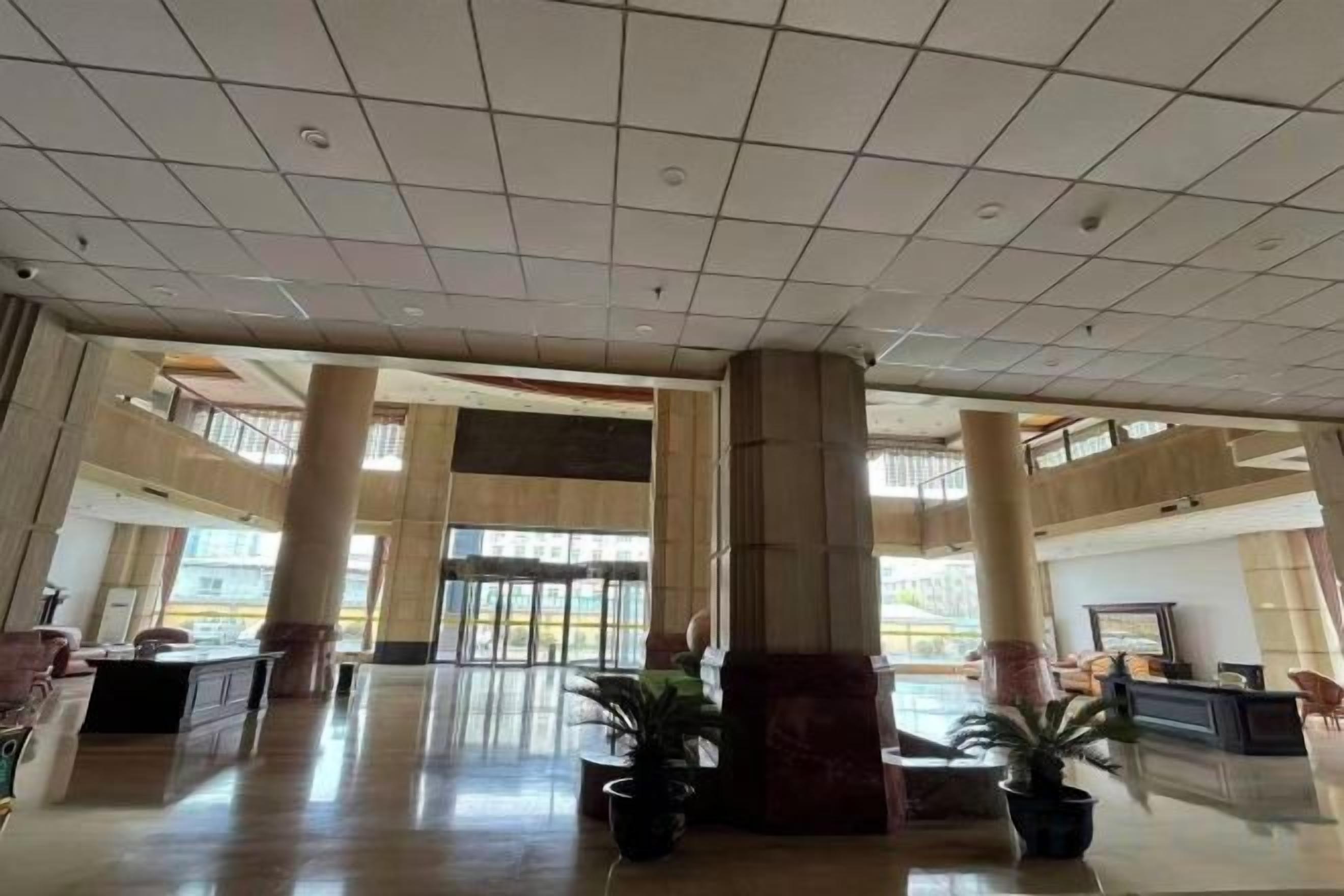 A spacious lobby with a high ceiling, large pillars, and a reception desk.