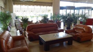 A spacious lobby with leather sofas, a central coffee table, and potted plants.
