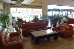 Un vestíbulo amplio con sofás de cuero, una mesa de centro y plantas en macetas.