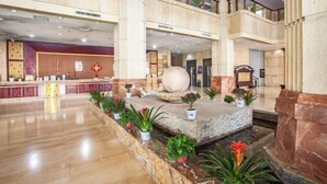 A spacious lobby with a marble floor, a reception desk, and a large decorative sphere. - Taoyuan International Hotel (Yuncheng)