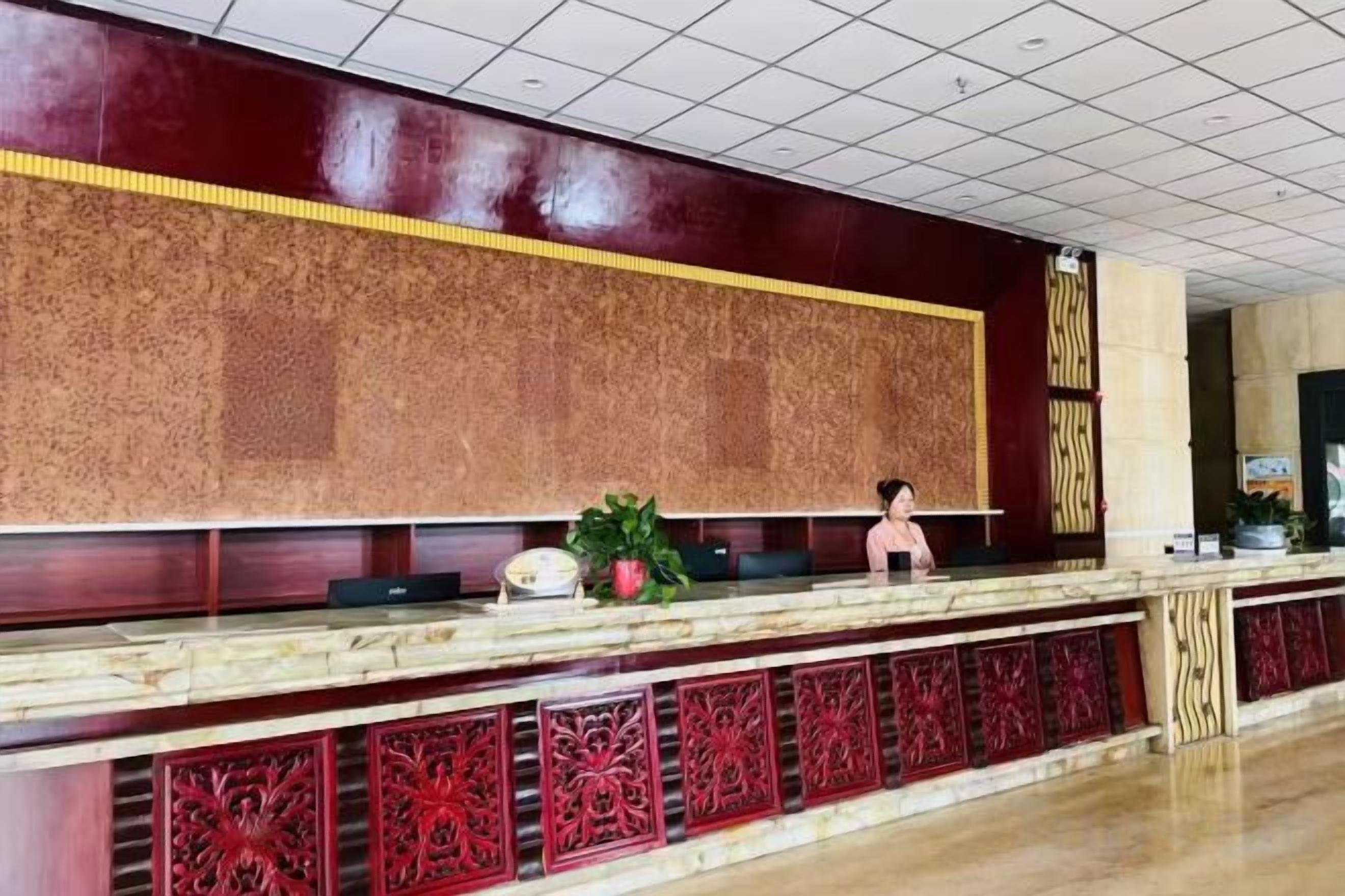 A reception desk with a marble top and intricate red paneling.