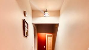 Un couloir étroit, doté d’un plancher en bois et d’une porte rouge au fond.