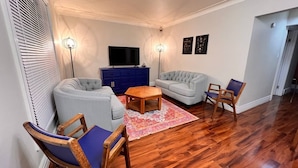 Un salon avec deux canapés, une table basse et un téléviseur posé sur un meuble bleu.
