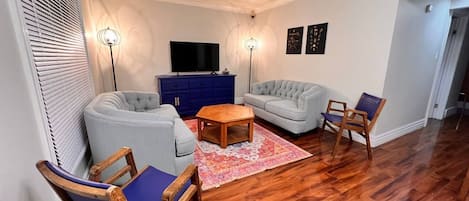 A living room with two sofas, a coffee table, and a TV on a blue cabinet.
