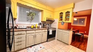 Une cuisine avec des meubles de couleur jaune, une cuisinière et un réfrigérateur.