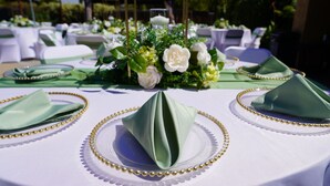 A table set with green napkins, gold bead trim, and white plates.