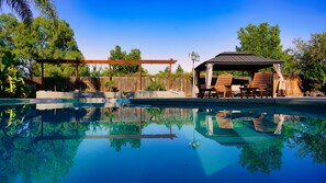A clear swimming pool with a wooden deck and lounge chairs. - Fernwood Retreat at Madera Ranchos (Madera)